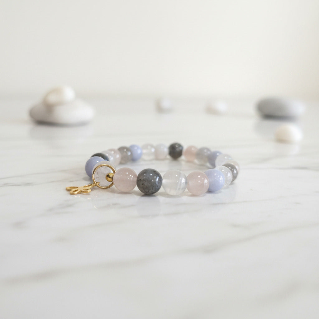 Pastel gemstone bracelet with gold charm on marble, serene zen aesthetic