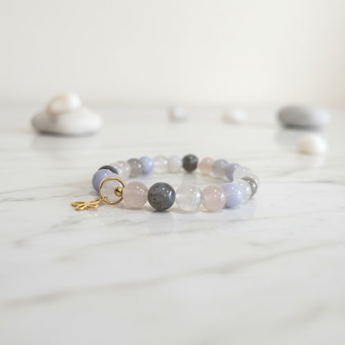 Pastel gemstone bracelet with gold charm on marble, serene zen aesthetic