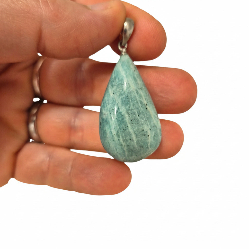 Teardrop-shaped blue stone held between fingers with a white background .