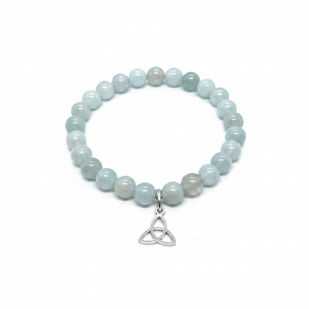 Beaded bracelet with a Trinity knot charm on a stone surface