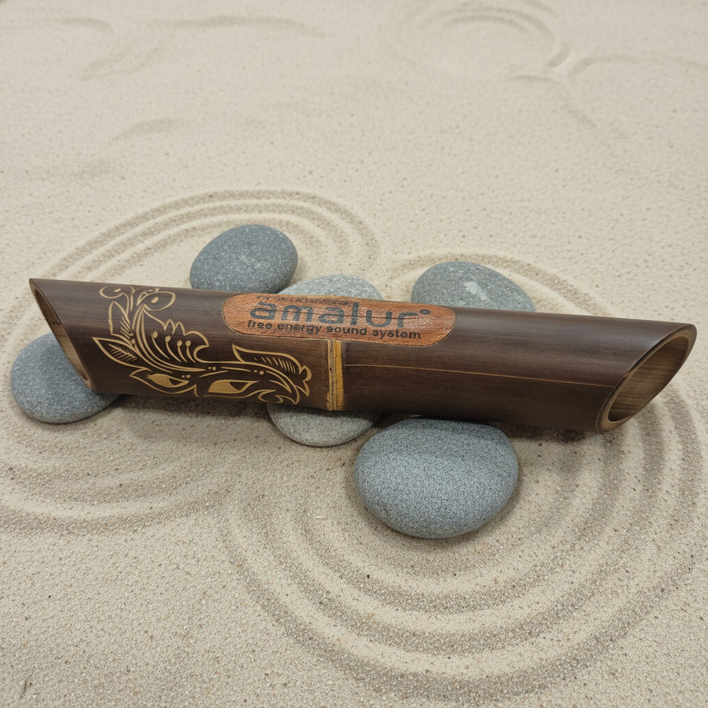 Bamboo speaker with 'Amalur' branding on a sandy surface with stones.