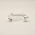 Clear bi-terminated crystal prism on a white surface