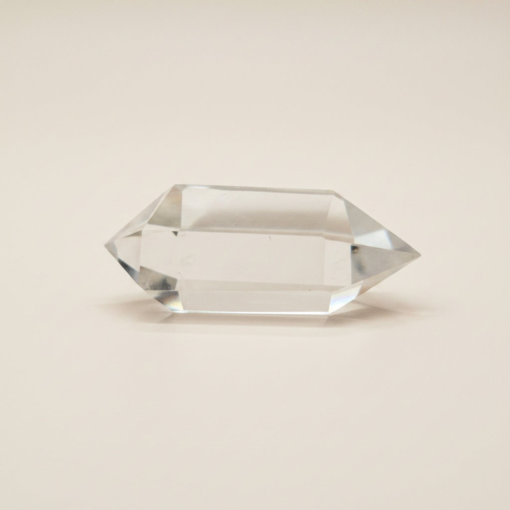 Clear bi-terminated crystal prism on a white surface