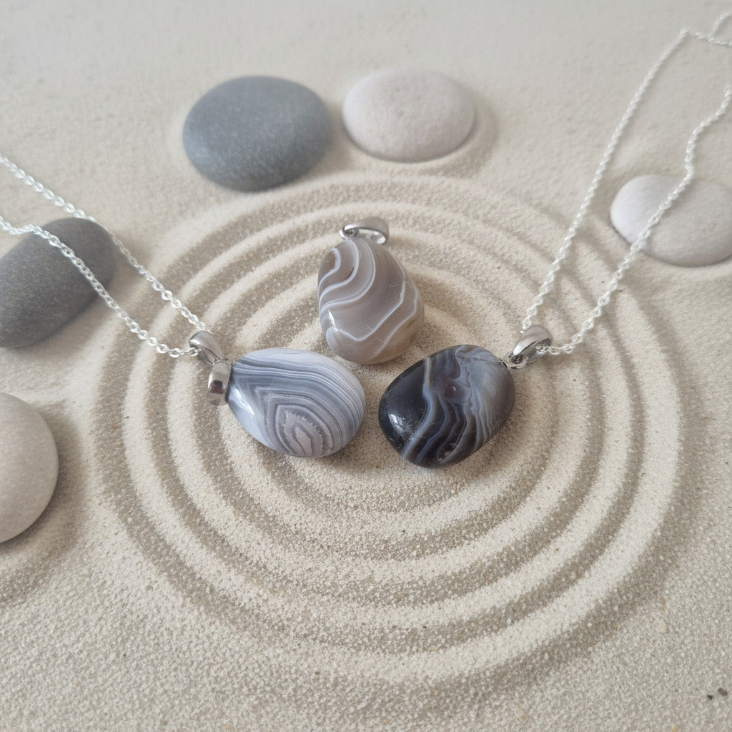 Agate stone pendants on a sandy surface with chain