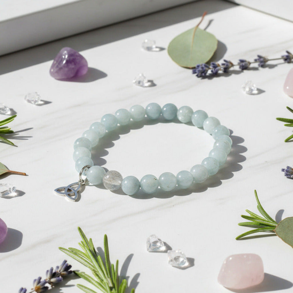 Light blue beaded bracelet with a silver Trinity knot charm on a light gray background