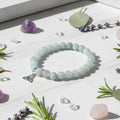 Light blue beaded bracelet with a silver Trinity knot charm on a light gray background