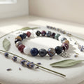 Multicolored beaded bracelet on a white surface with lavender flowers and leaves.