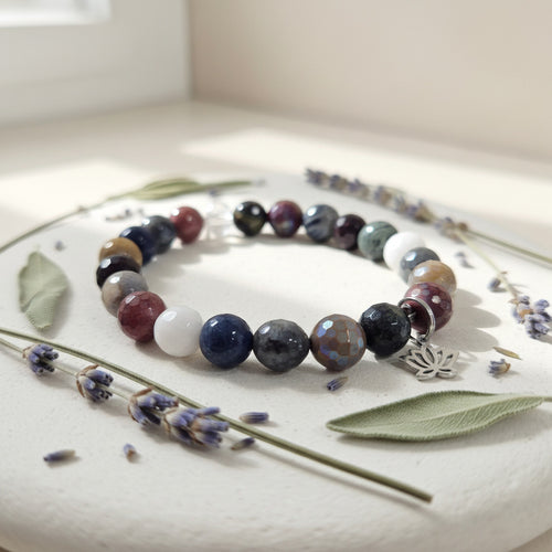 Multicolored beaded bracelet on a white surface with lavender flowers and leaves.