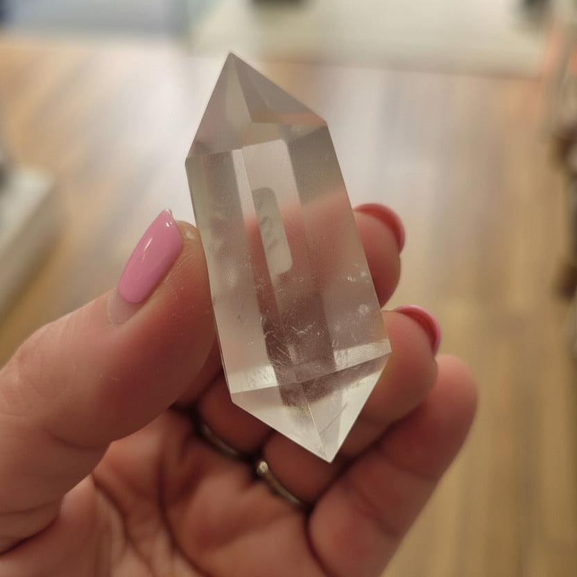 Clear crystal held in a hand with on a blurred background