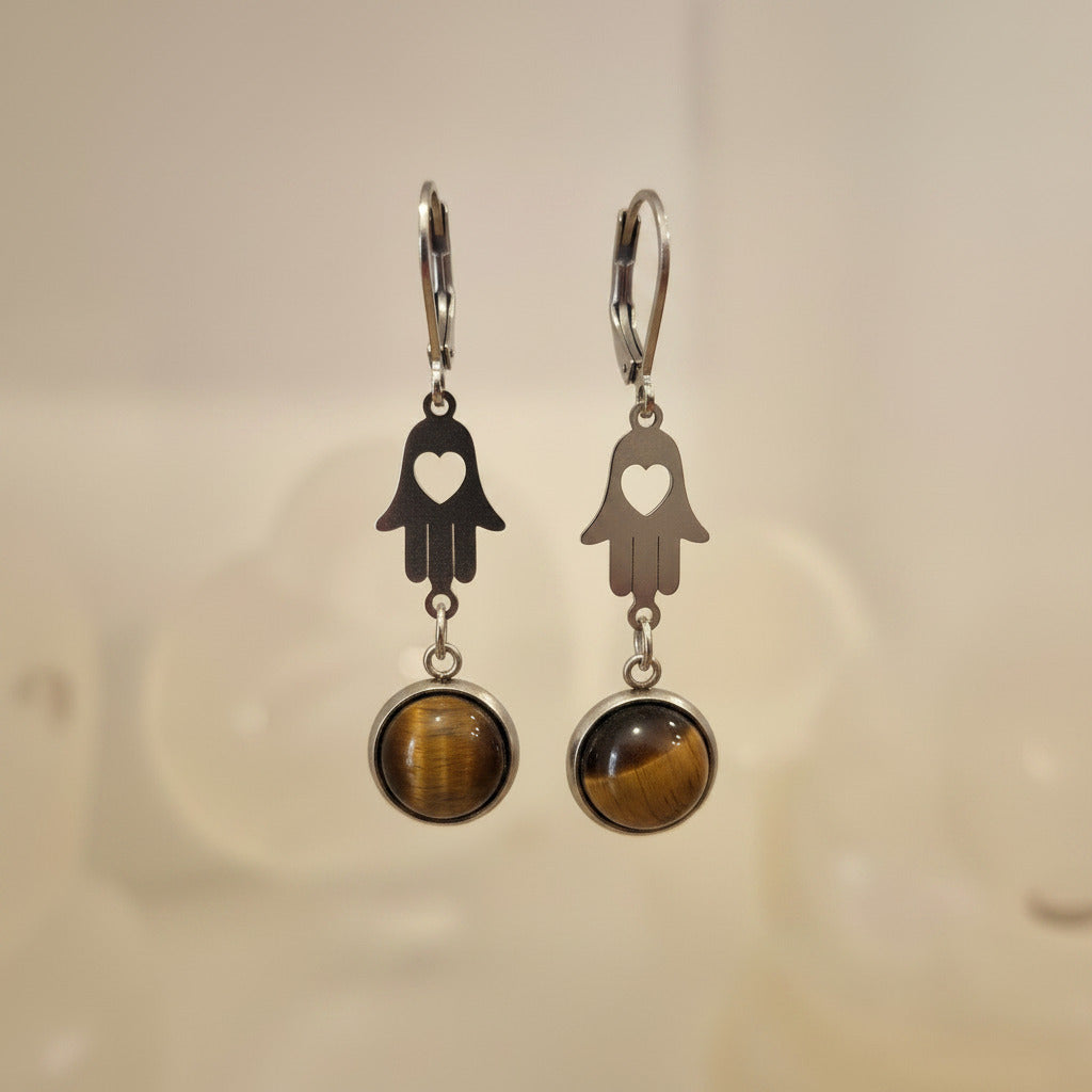 Pair of earrings with hamsa hand design and tiger's eye stones on a neutral background