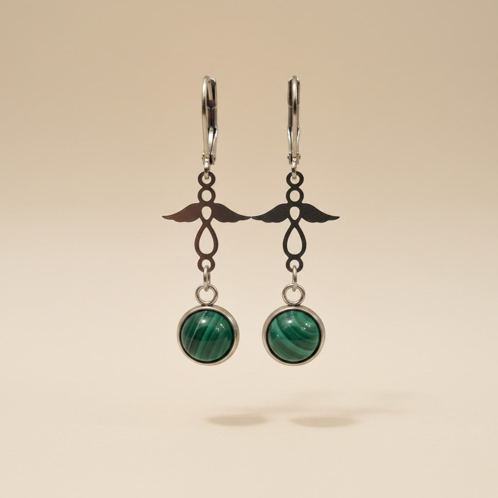 Pair of earrings with natural malachite and angel charm and silver hooks on a beige background