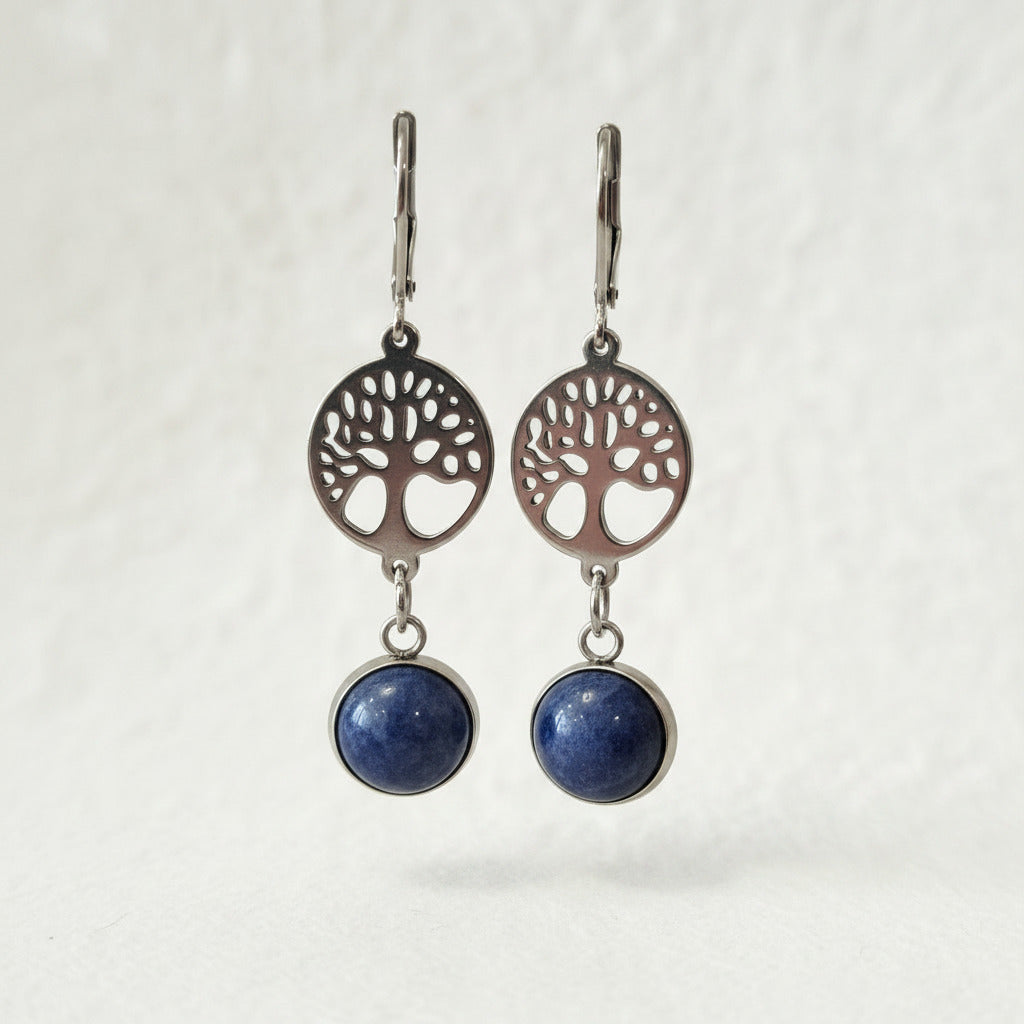 Pair of earrings with tree-of-life design and blue stones on a neutral background
