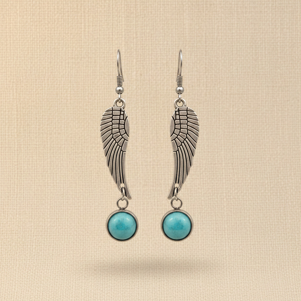 Silver wing-shaped earrings with turquoise stones on a beige background