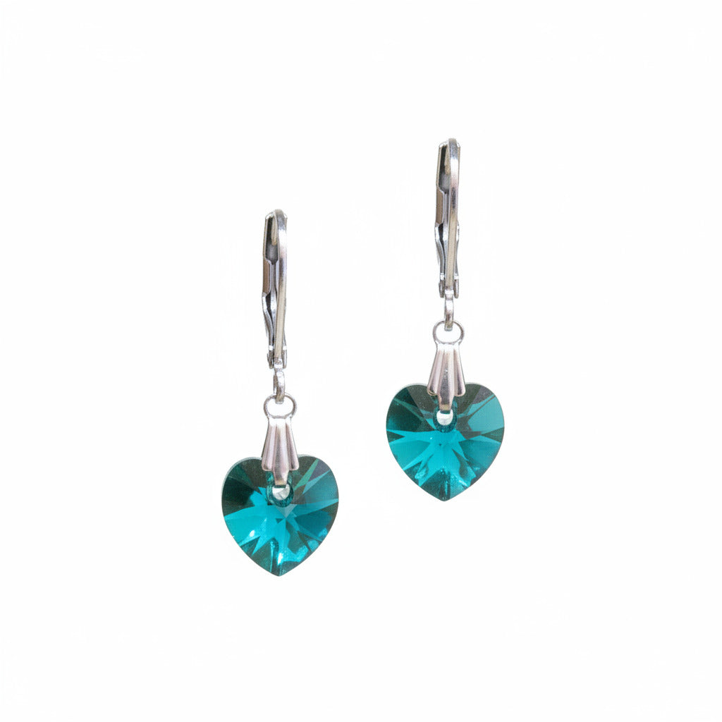 Pair of earrings with teal heart-shaped crystal on a white surface