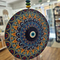 Decorative circular object with intricate patterns held in front of a blurred indoor background