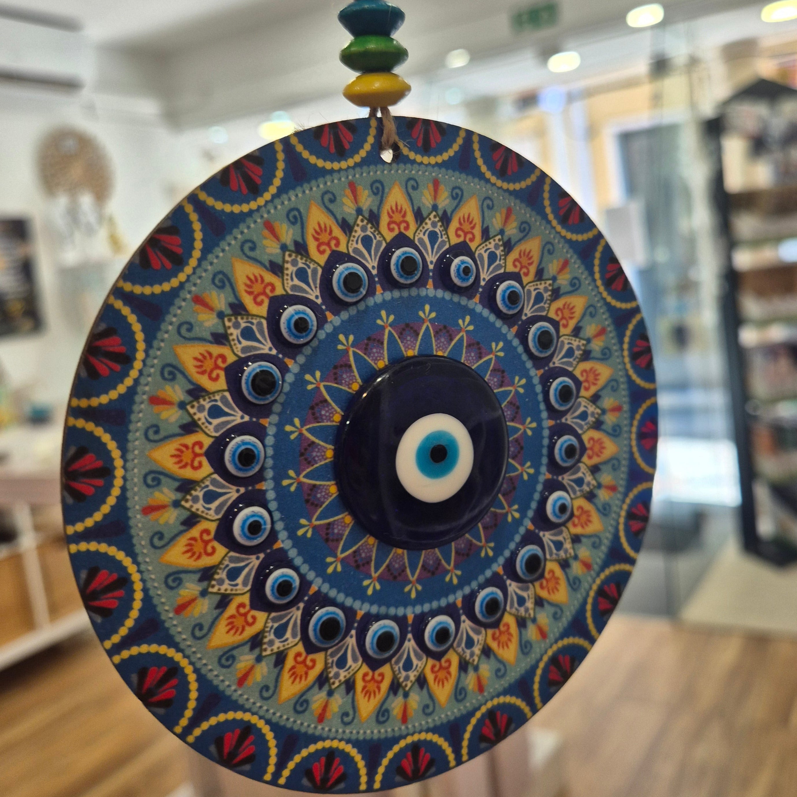 Decorative circular object with intricate patterns held in front of a blurred indoor background