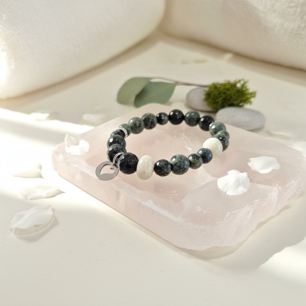Beaded bracelet on a pink stone with white flowers and green leaves