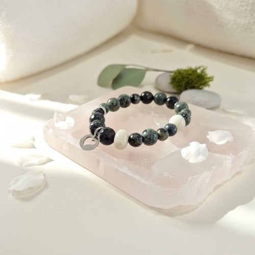 Beaded bracelet on a pink stone with white flowers and green leaves