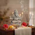 Statue of a deity with incense sticks, flowers, and candles on a table.