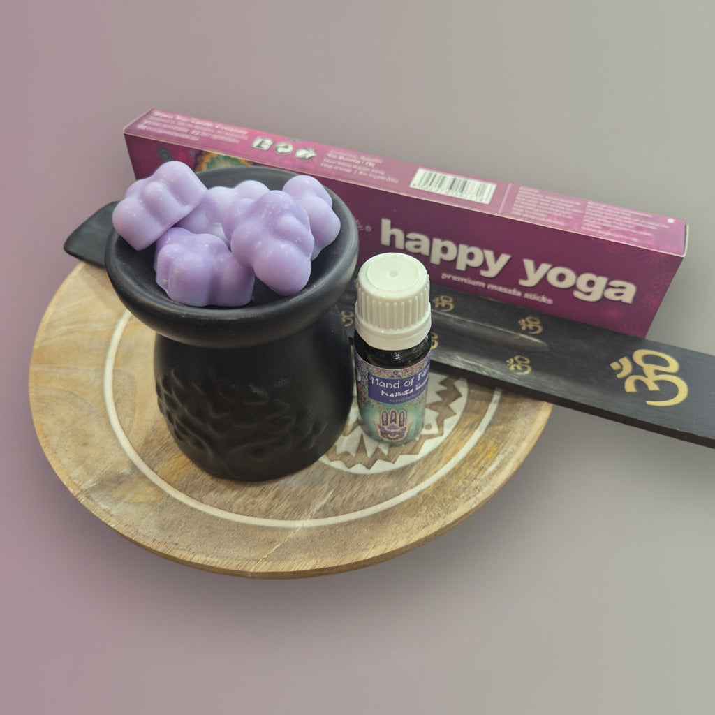 Incense with wooden holder, fragrance oil and purple candles in a ceramic holder on a wooden surface