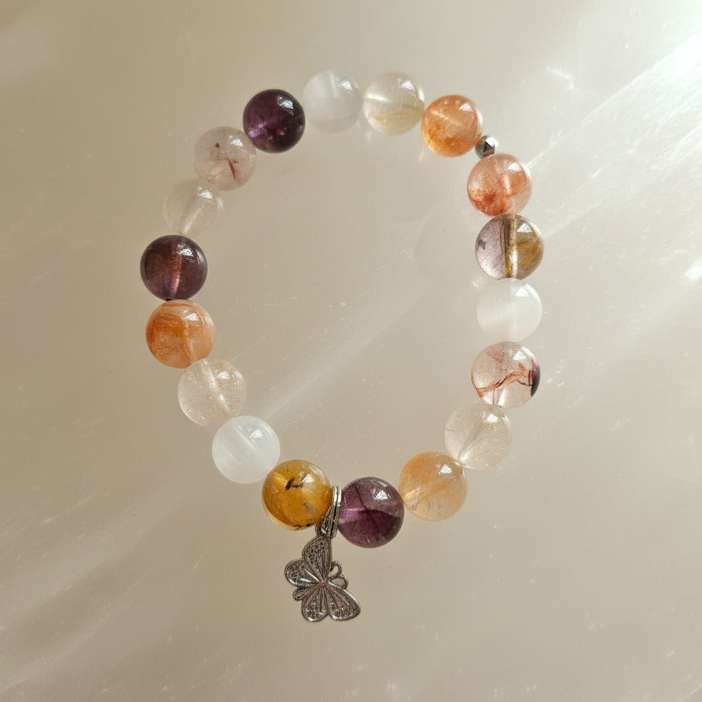 Quartz beaded bracelet with a silver butterfly charm on a beige background