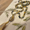 Necklace with stone pendant and tassel on a fabric background with leaves