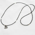 Necklace with black beads and a small charm on a white background