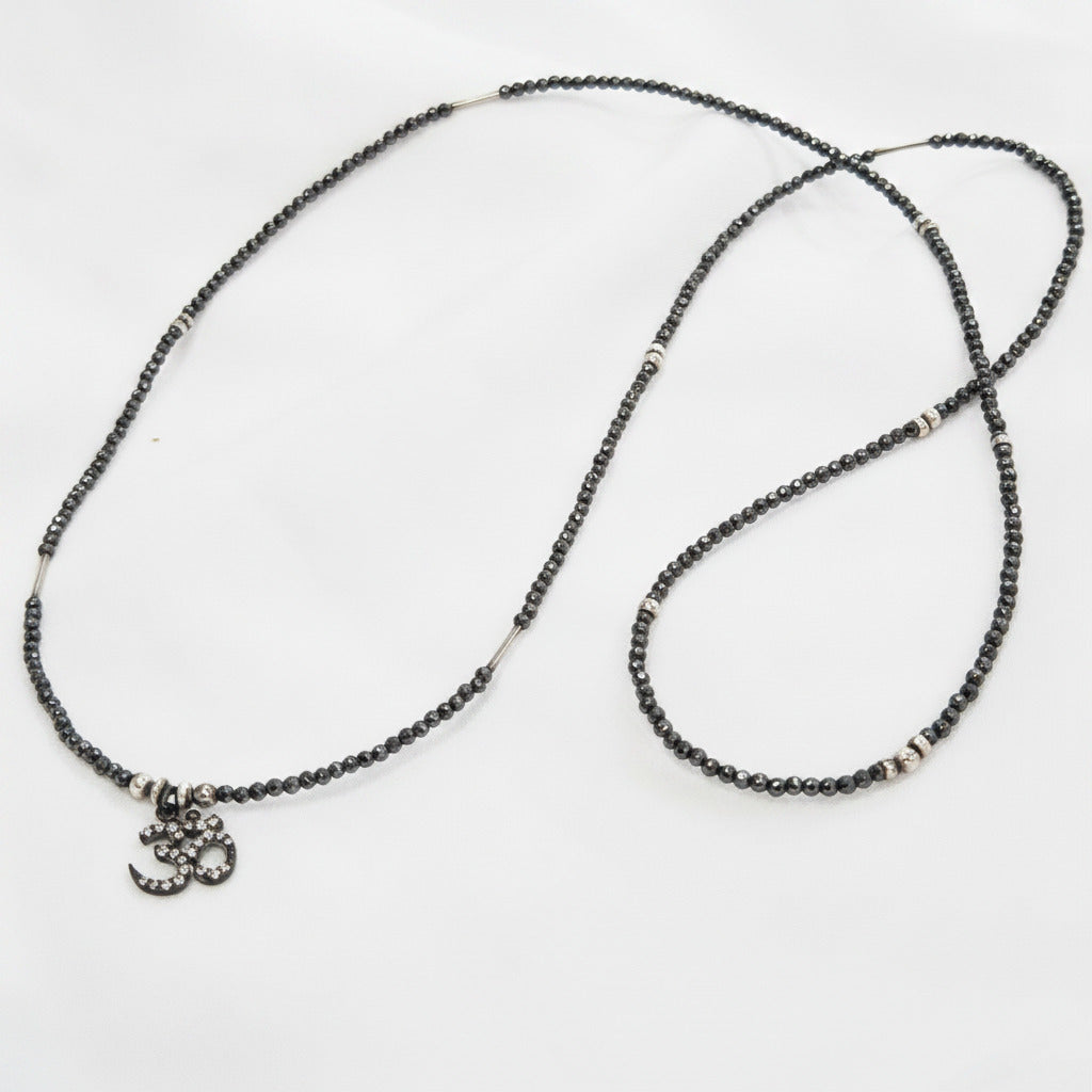 Necklace with black beads and a small charm on a white background