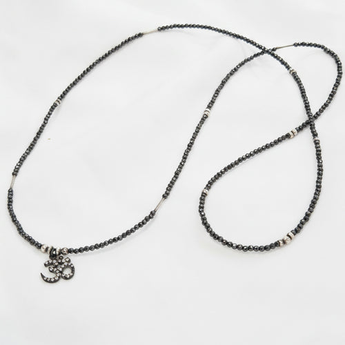 Necklace with black beads and a small charm on a white background