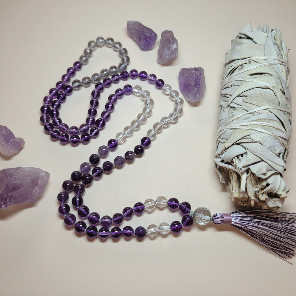 Purple beaded necklace with crystals and sage on a light background