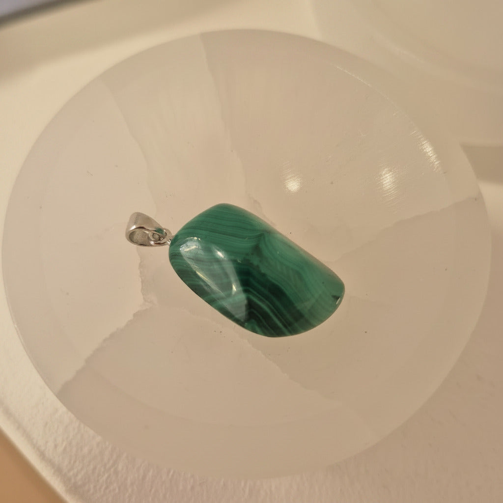 Green malachite stone pendant on a white selenite bowl 