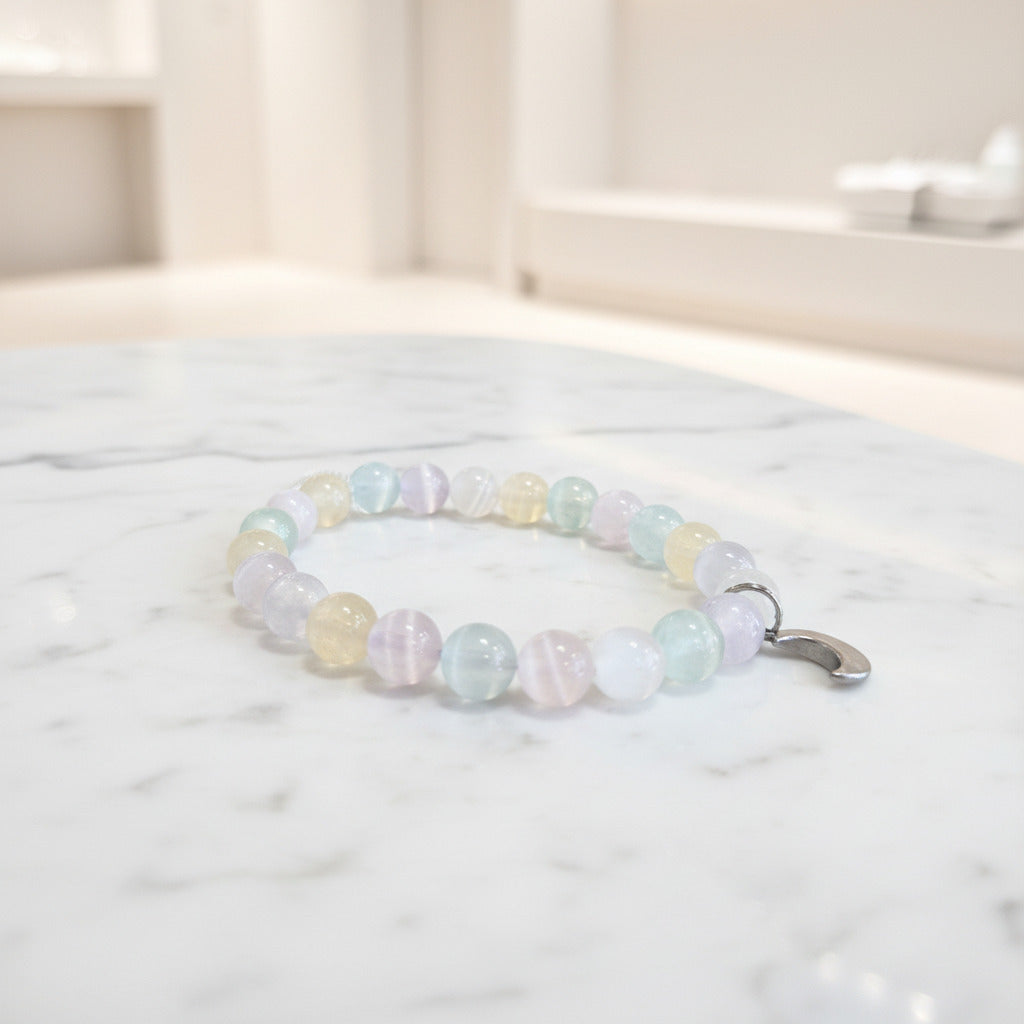 Beaded bracelet with a stainless steel moon charm a marble surface