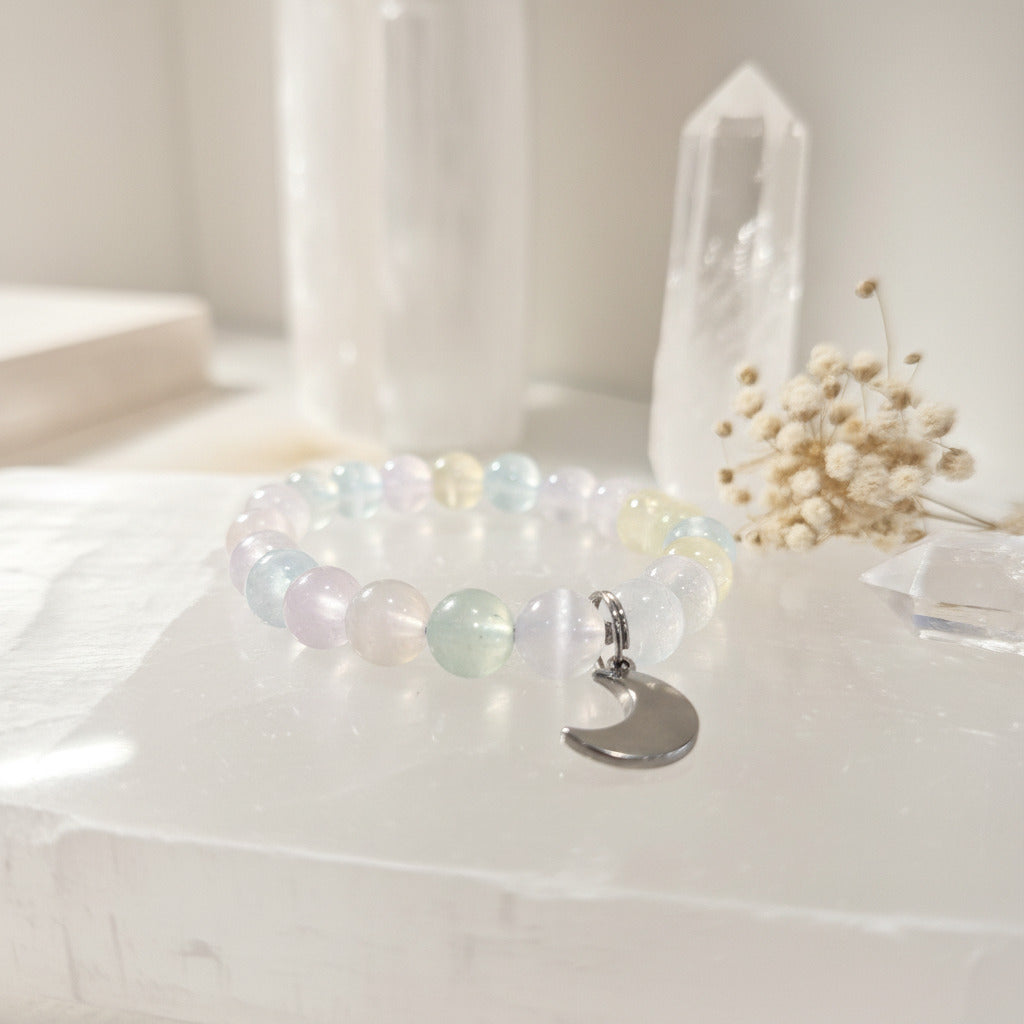 Bracelet with a moon charm on a white surface with a soft focus background