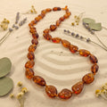 Amber necklace on a textured surface with dried flowers and leaves
