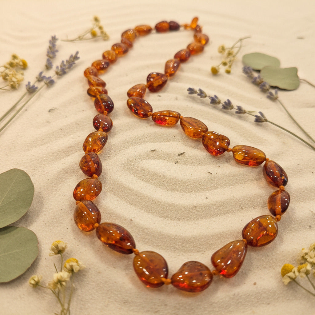 Amber necklace on a textured surface with dried flowers and leaves