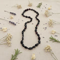 Black Amber Necklace on a light fabric background with dried flowers