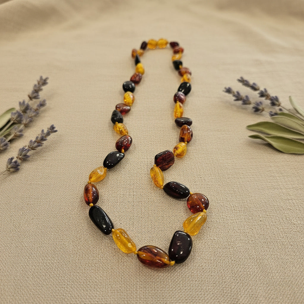 Amber Necklace with multicolored beads on a beige fabric background with lavender and green leaves.