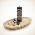Black spiritual candle on a wooden table with palm stones and palo santo.