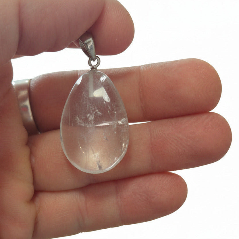 Clear teardrop-shaped pendant held in a hand with a white background