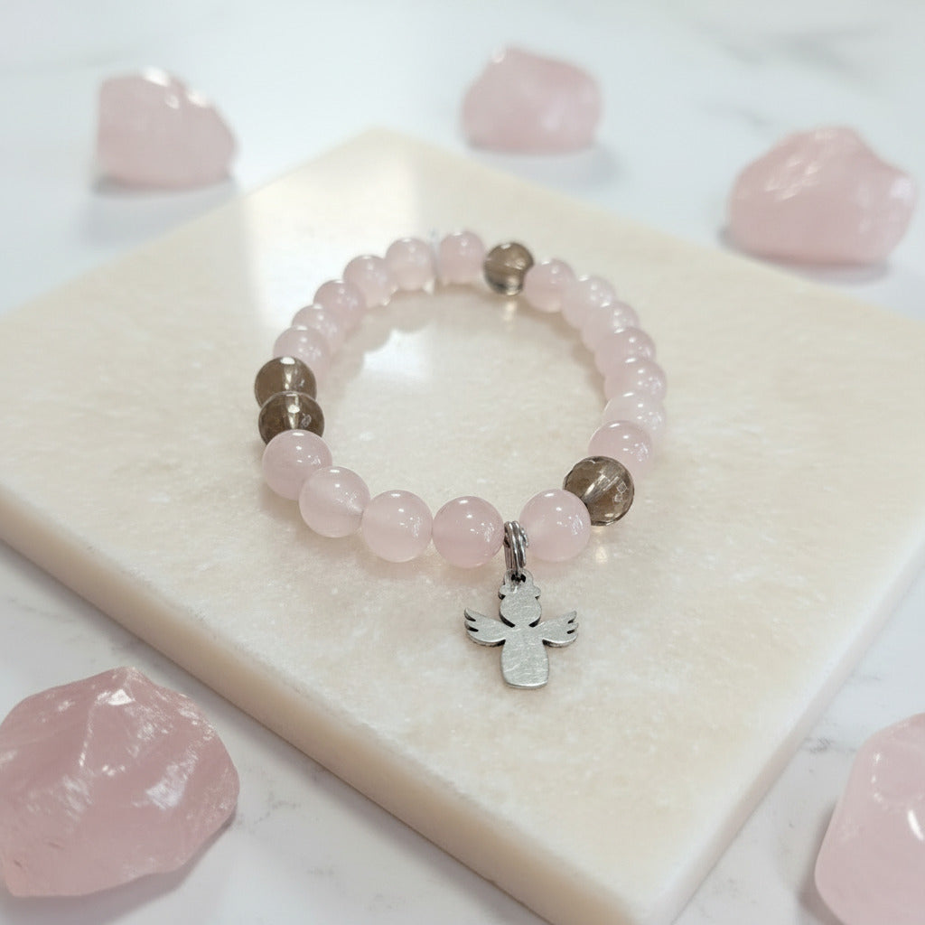Pink beaded bracelet with a stainless steel charm on a white surface with pink stones.