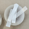 small selenite sticks on a beige fabric background