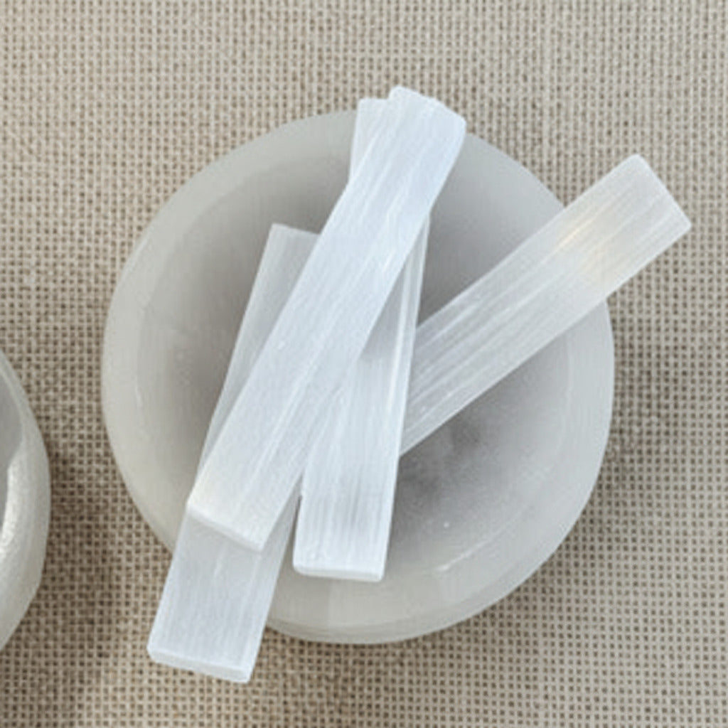small selenite sticks on a beige fabric background