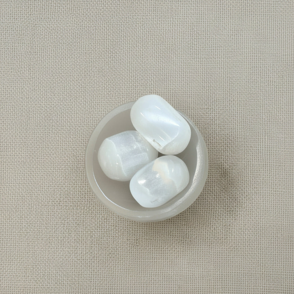 tumbled selenite stones on a beige fabric background