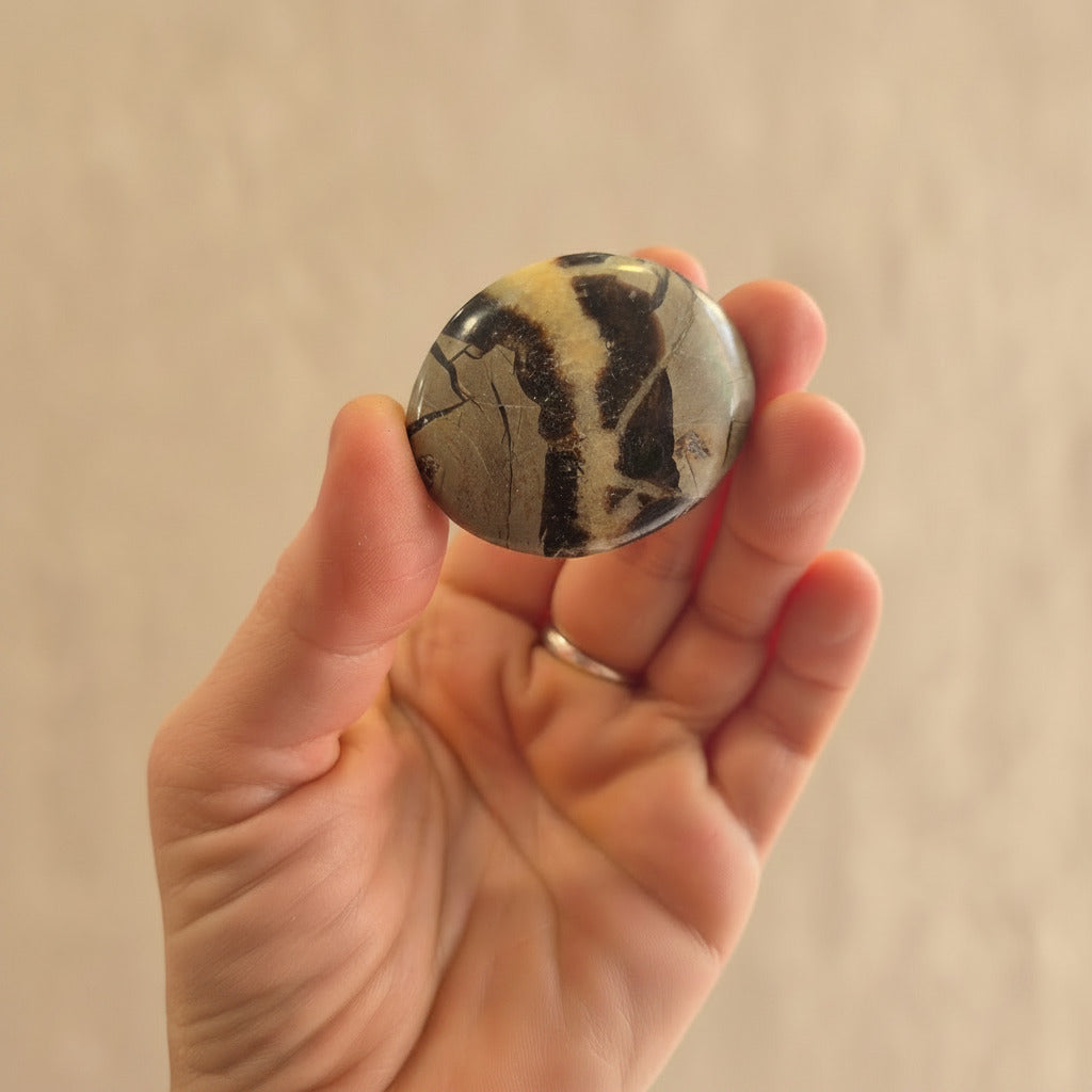 Hand holding a marbled stone in beige background