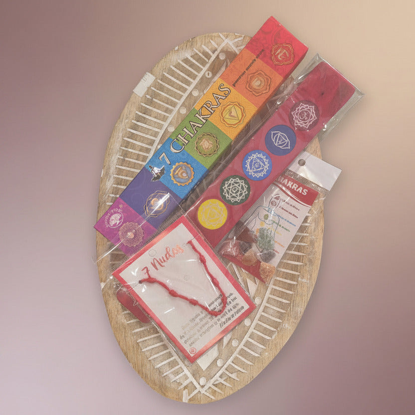 Seven chakras incense with colorful incense holder and stones and a red bracelet on a wooden surface