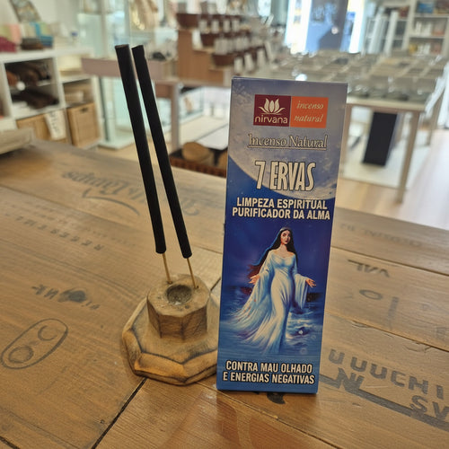 Incense stick holder with incense sticks and a box labeled '7 Ervas' on a wooden surface.