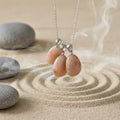 natural sunstone pendants hang on a chain over sand with stones around