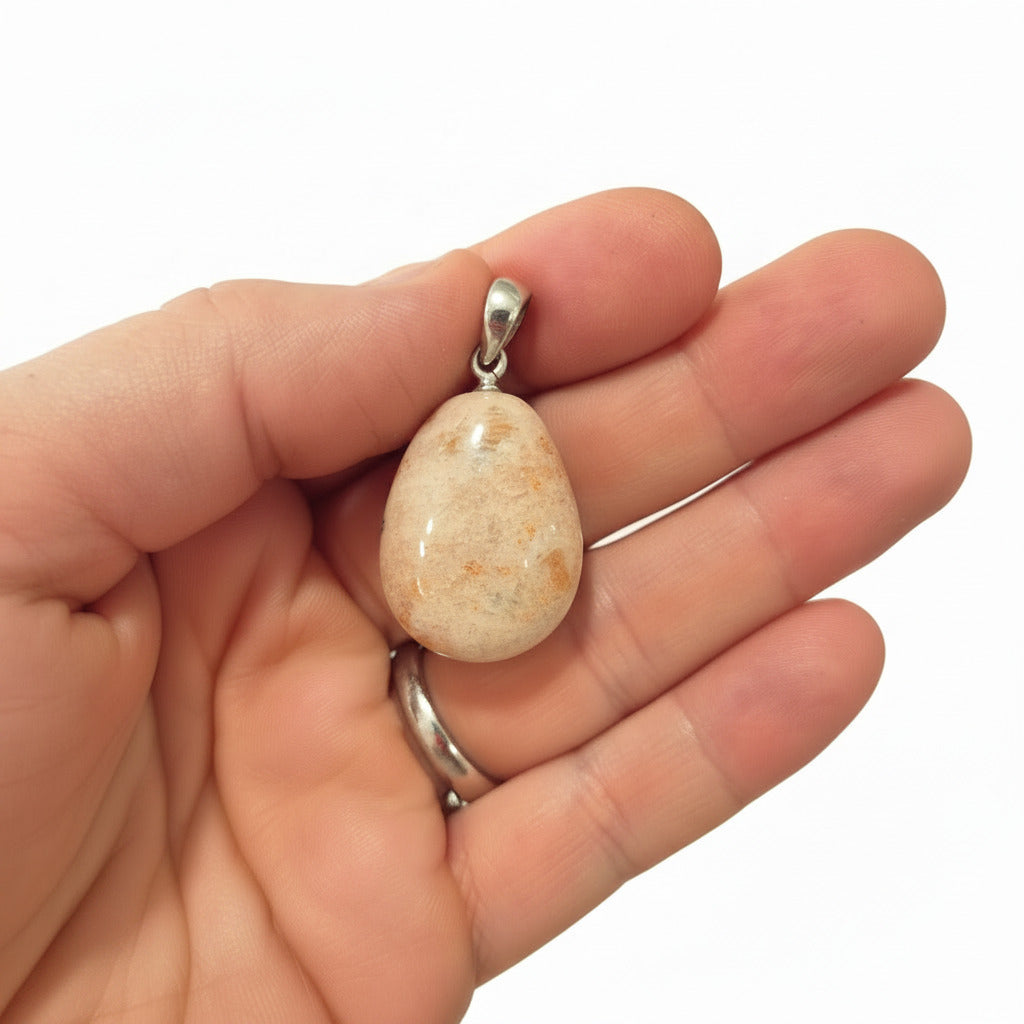 Hand holding a stone pendant with a white background