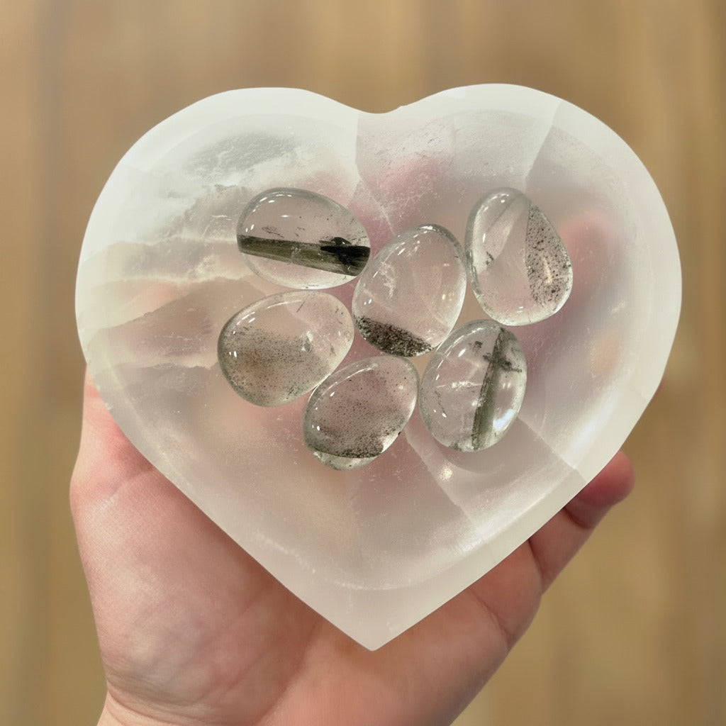 Heart-shaped crystal mold with clear crystals inside, held by a hand against a blurred background