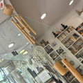 Decorative wooden wind-chime hanging in a room with shelves and lights.